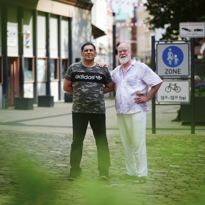 Zwei Männer stehen in einer Straße nebeneinander (vergrößerte Bildansicht wird geöffnet)